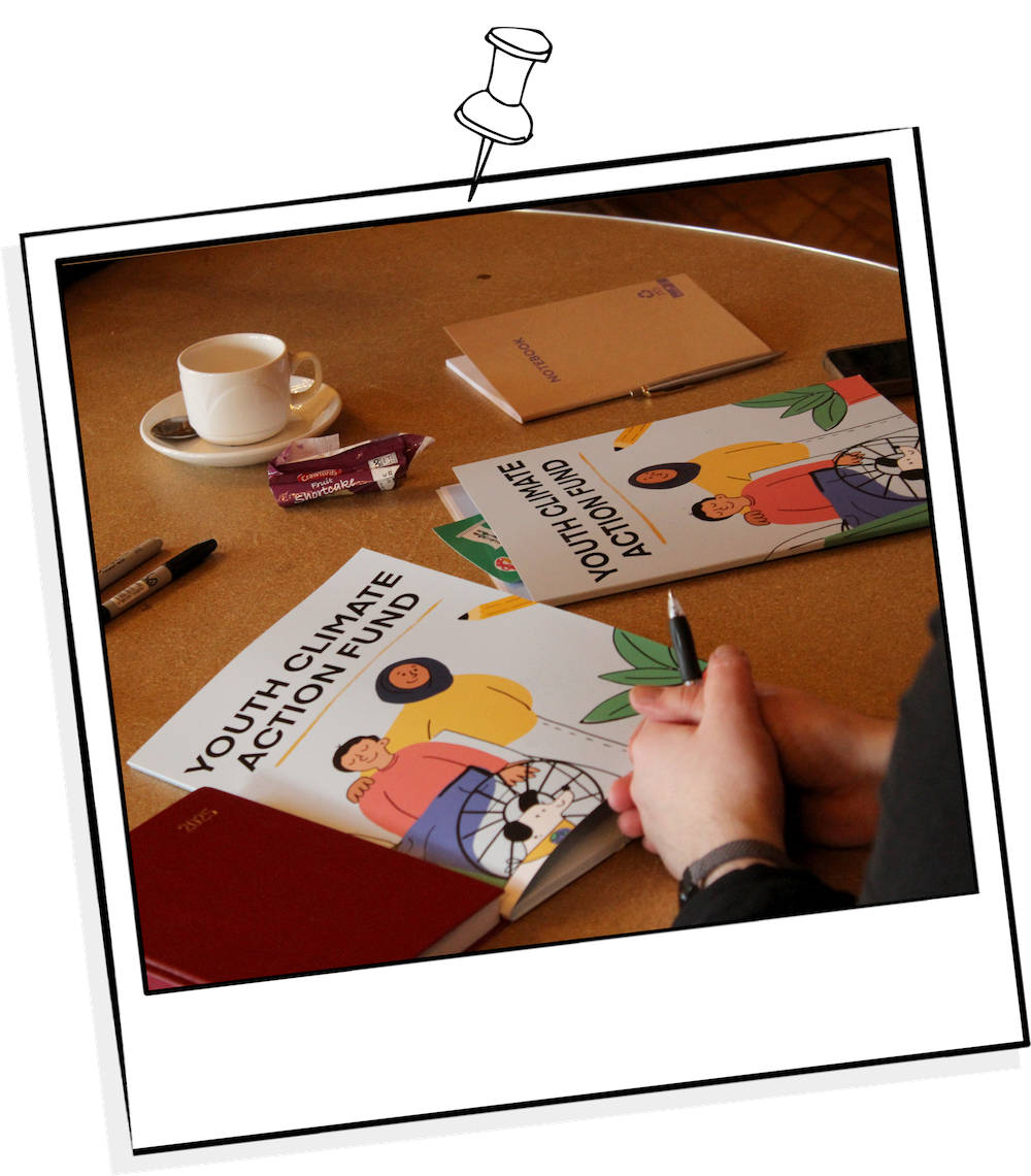 Polaroid photograph from the Youth Climate Action Fund kick-off event showing branded folders on the tables and participants engaging with the materials